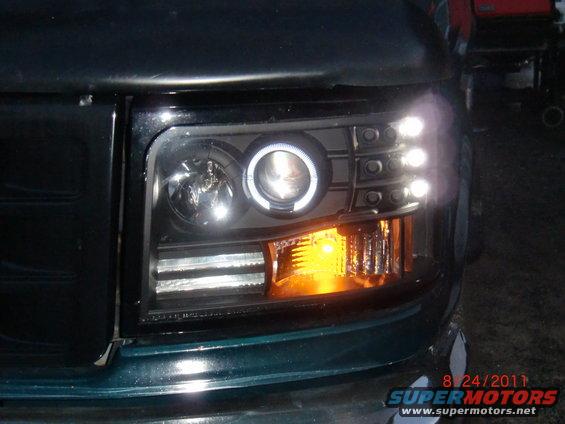 Dark green vehicle's aftermarket headlight assembly with halo ring and amber turn signal