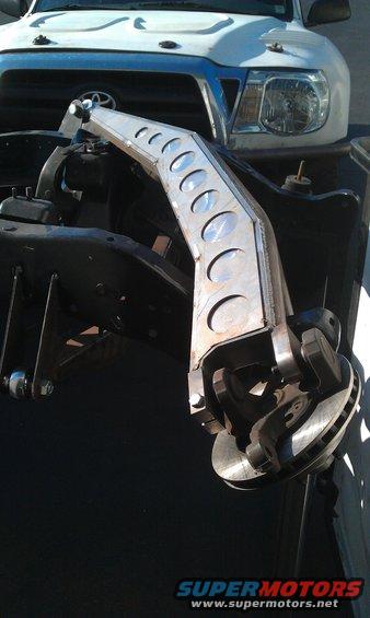 Custom suspension arm attached to a white Toyota Tacoma's frame