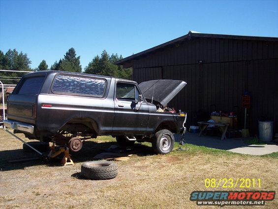 1978 Ford Bronco with hood open, rear lifted on jack stands, and front wheel removed