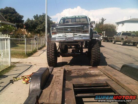 Front view of a lifted Ford pickup truck with large tires on a trailer, license plate 8X31267