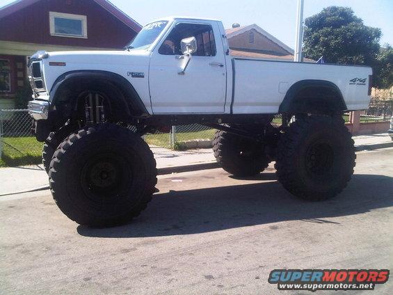 White lifted Ford pickup truck with large tires, side view