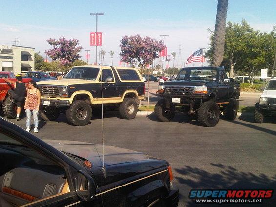 Two-tone black and tan lifted Ford Bronco parked next to a lifted black pickup truck