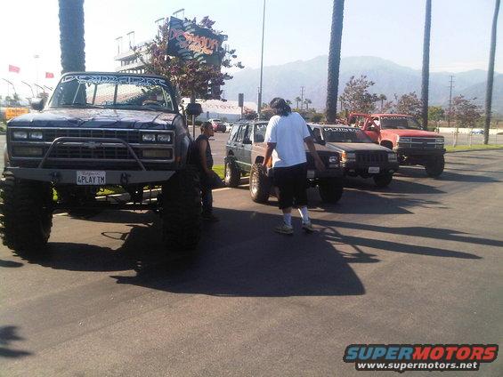 Dark blue pickup truck with large tires and custom bumper, front view. License plate reads '4PLAY TM'