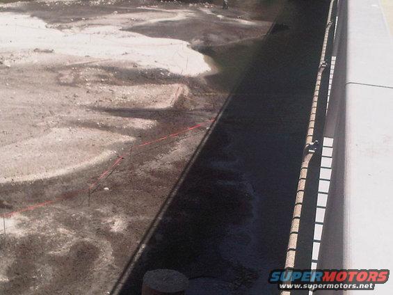 Construction site with red string lines marking out an area, wet ground, and a concrete barrier