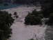 1986 Ford Bronco - A wide shot of a dry lake bed with trees and a body of water. The Supermotors logo is visible in the lower right corner.