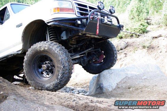 White 1995 Ford Bronco on a rock with off-road tires and a brush guard