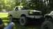 1989 Ford Bronco - A lifted tan Ford Bronco is parked on grass next to another off-road vehicle.