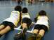 1987 Ford Bronco - Three young athletes in matching uniforms lie on the mat, observing a wrestling competition.