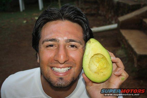 Man with beard and white shirt holds half an avocado. "SUPERMOTORS.NET" logo in lower right
