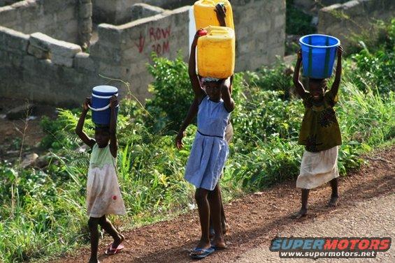 Children carry yellow and blue water containers on their heads