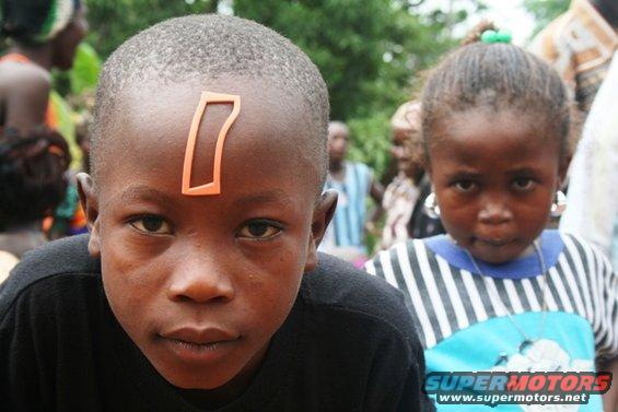 Two children, one with an orange marking on forehead, the other wearing large earrings