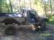 1989 Ford Bronco - Off-road pickup truck with a roll cage navigates a muddy trail.