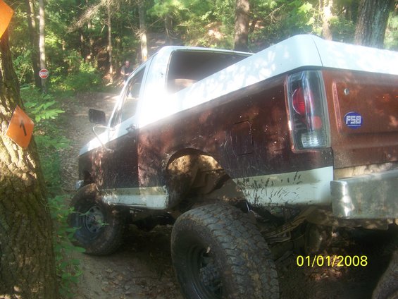 Muddy Ford Bronco on a trail, looks like it's from the late 80s