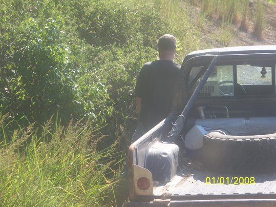 Pickup truck bed with spare tire and a man standing beside it, outdoors