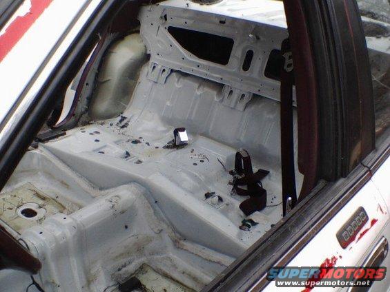 Stripped car interior, white floor, roll cage, seatbelt, red and white exterior stripe