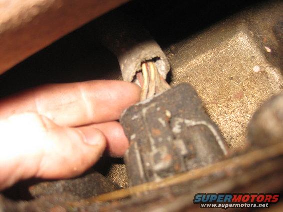 Hand holding a damaged wiring harness connector with exposed wires