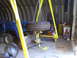 1992 Ford Bronco - A blue tractor sits in a garage, with a large tire being held by a yellow gantry above its front loader.
