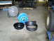 1992 Ford Bronco - Vehicle chassis and various parts, including a fan, blue wheel, and tire components, are laid out on a concrete floor.