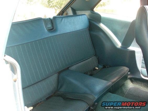 Back seat of a car, blue upholstery with vertical stitching, seat belts visible
