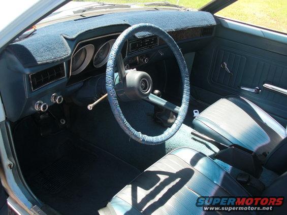 1972 Ford Pinto interior with blue seats, dashboard, and steering wheel cover