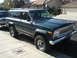 1972 Ford Pinto - This dark green Jeep Cherokee, likely a 1974 model, is seen from a 3/4 front angle with its chrome grille and roof rack visible.