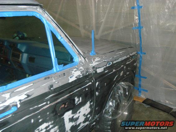 Car bodywork with blue tape and primer visible