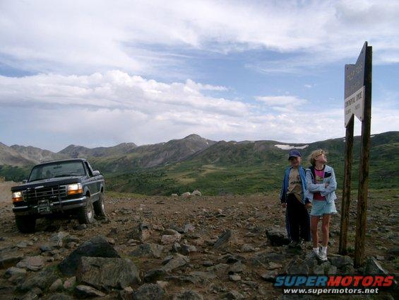 1995 Ford F-150 pickup truck parked on a rocky mountain trail with two children standing nearby