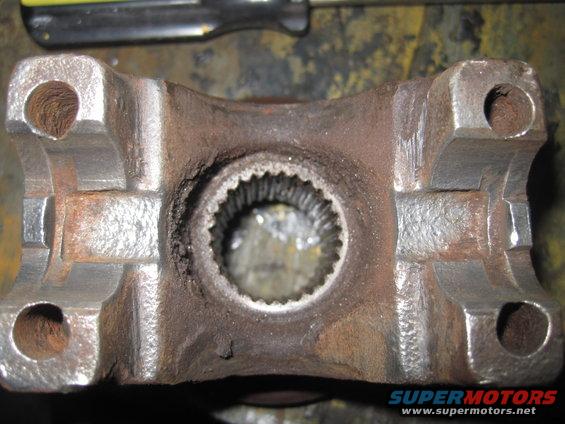Rusty driveshaft U-joint yoke with splined opening and four bolt holes