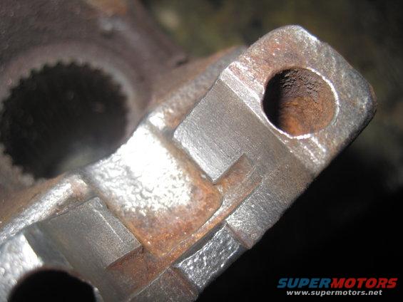 Close-up of a rusty metal component with internal splines and a bolt hole