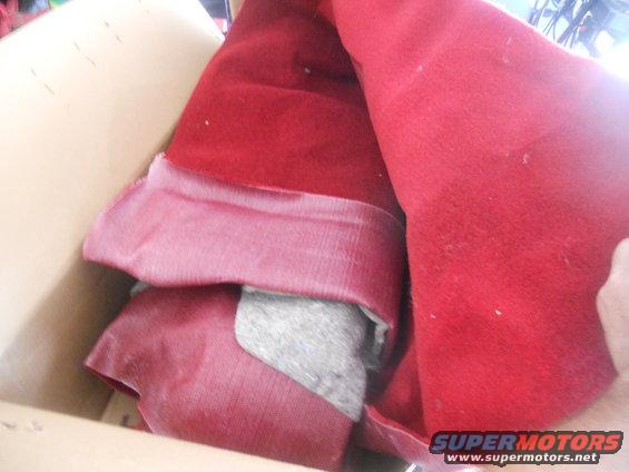 Box with folded red carpet and padding inside