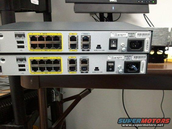 Two Cisco 1811 network switches stacked, showing rear ports and power switches