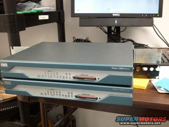 Two stacked Cisco 1800 Series network routers on a desk