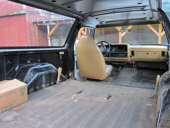 Interior of a disassembled truck, tan seats, black interior panels, cardboard box with jalapenos label