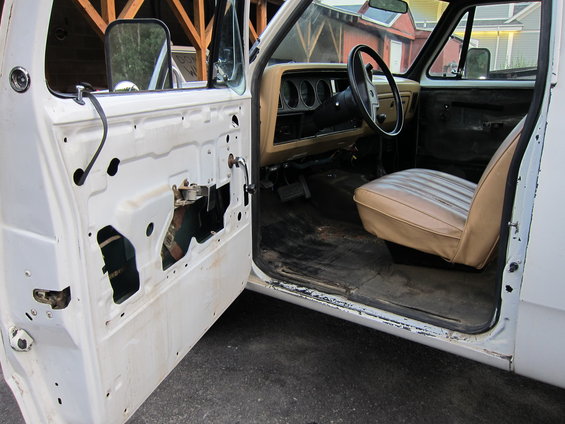 Interior of a white Dodge Ram pickup truck, showing the driver's seat, dashboard, and door panel removed