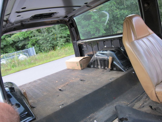 Interior of a truck bed with a tan seat and a cardboard box