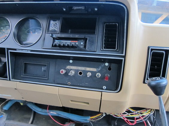 Vehicle dashboard with gauges, radio, and aftermarket switches. Tan interior