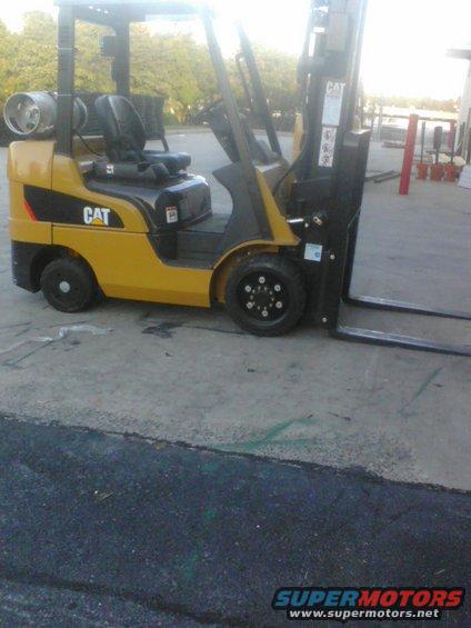Yellow CAT forklift with propane tank on the side, parked on concrete