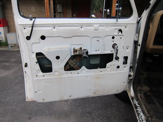 Inside of a white vehicle door, showing the window mechanism and door handle