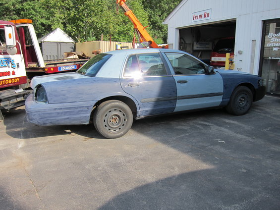 Side view of a blue sedan with primer on the rear quarter panel and front fender