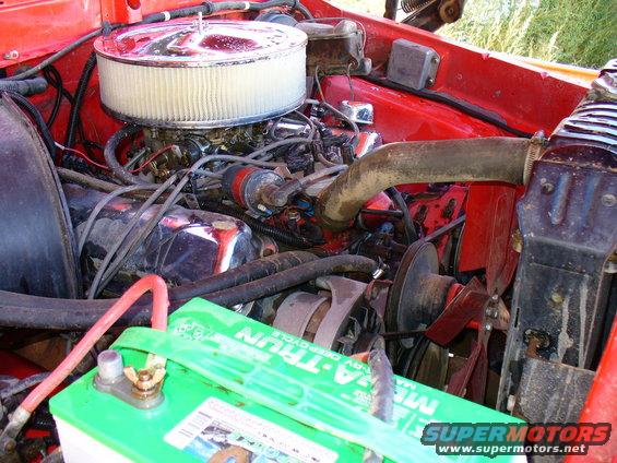 Red 1979 Ford Bronco engine bay with chrome air cleaner, visible battery, and hoses