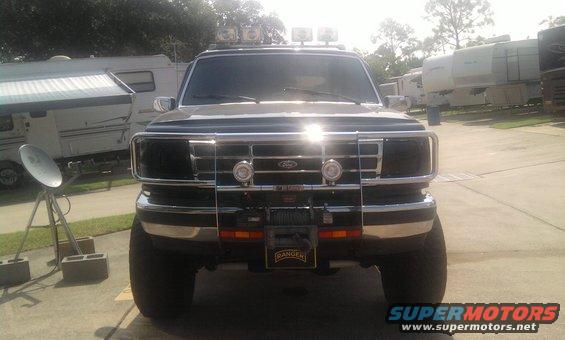 Black Ford truck front view with chrome grille, winch, and roof-mounted lights