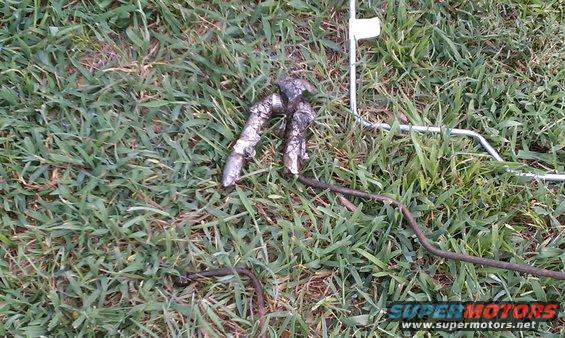 Metal car part on grass with Supermotors logo