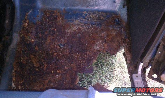 rusted floor pan inside a vehicle, showing significant corrosion and holes