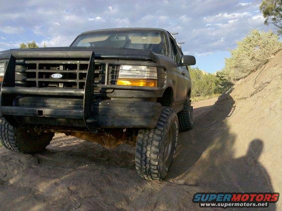 Black Ford Bronco on dirt road, front end visible with brush guard