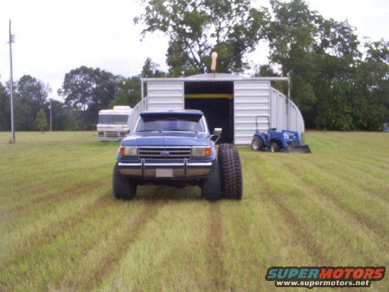 Blue pickup truck with oversized tires, front view
