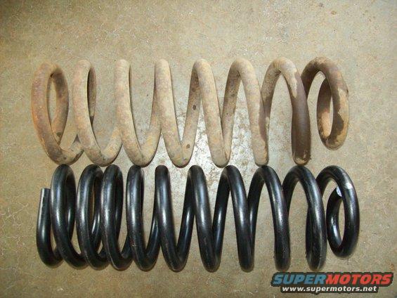 Rusty coil spring next to a new black coil spring