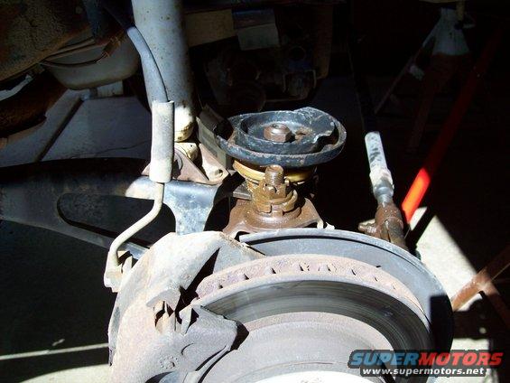Close-up of a vehicle's front suspension components, including a brake rotor and shock absorber mount