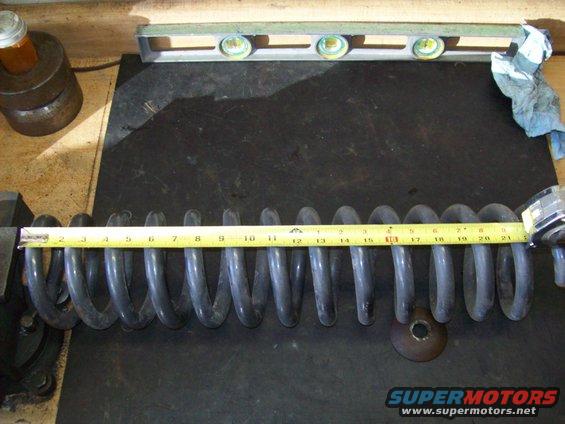 Coil spring being measured with a tape measure. A level is in the background