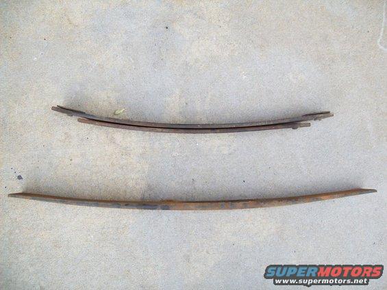 Two rusty leaf springs on concrete. The top one is a stack of three, the bottom one is a single spring