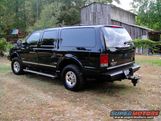 black Ford Excursion parked in front of a wooden building